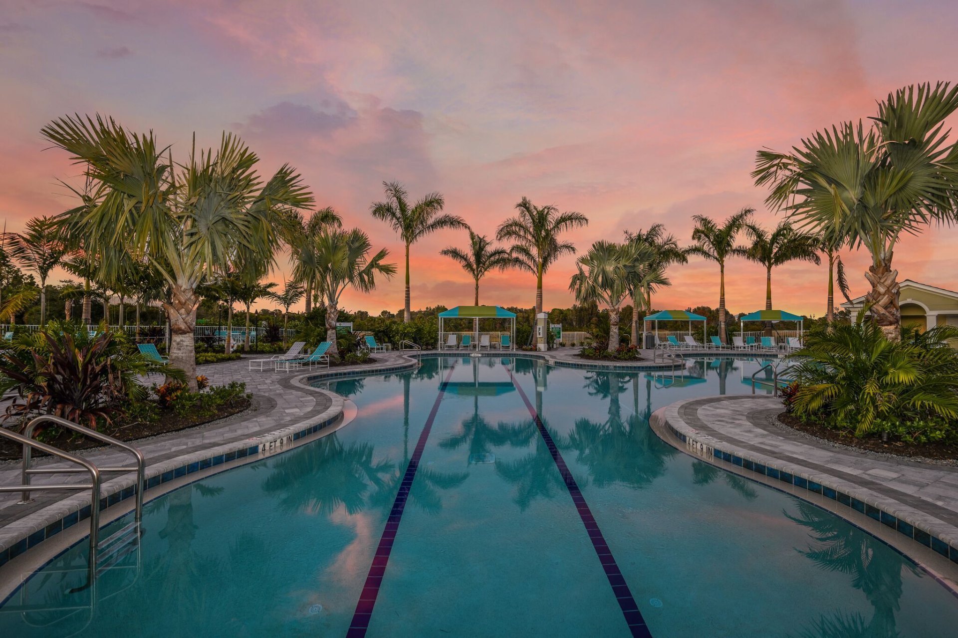 Luxury amenity center pool at sunset framed by palms — Boca Royale