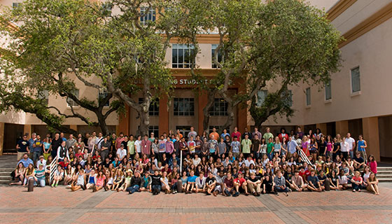 Large group photo of Ringling College students and faculty gathered in the campus courtyard under live oaks