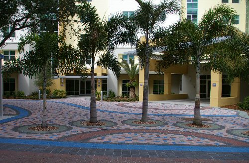 Palm-lined courtyard entry at Ringling College with patterned pavers and warm yellow building facades