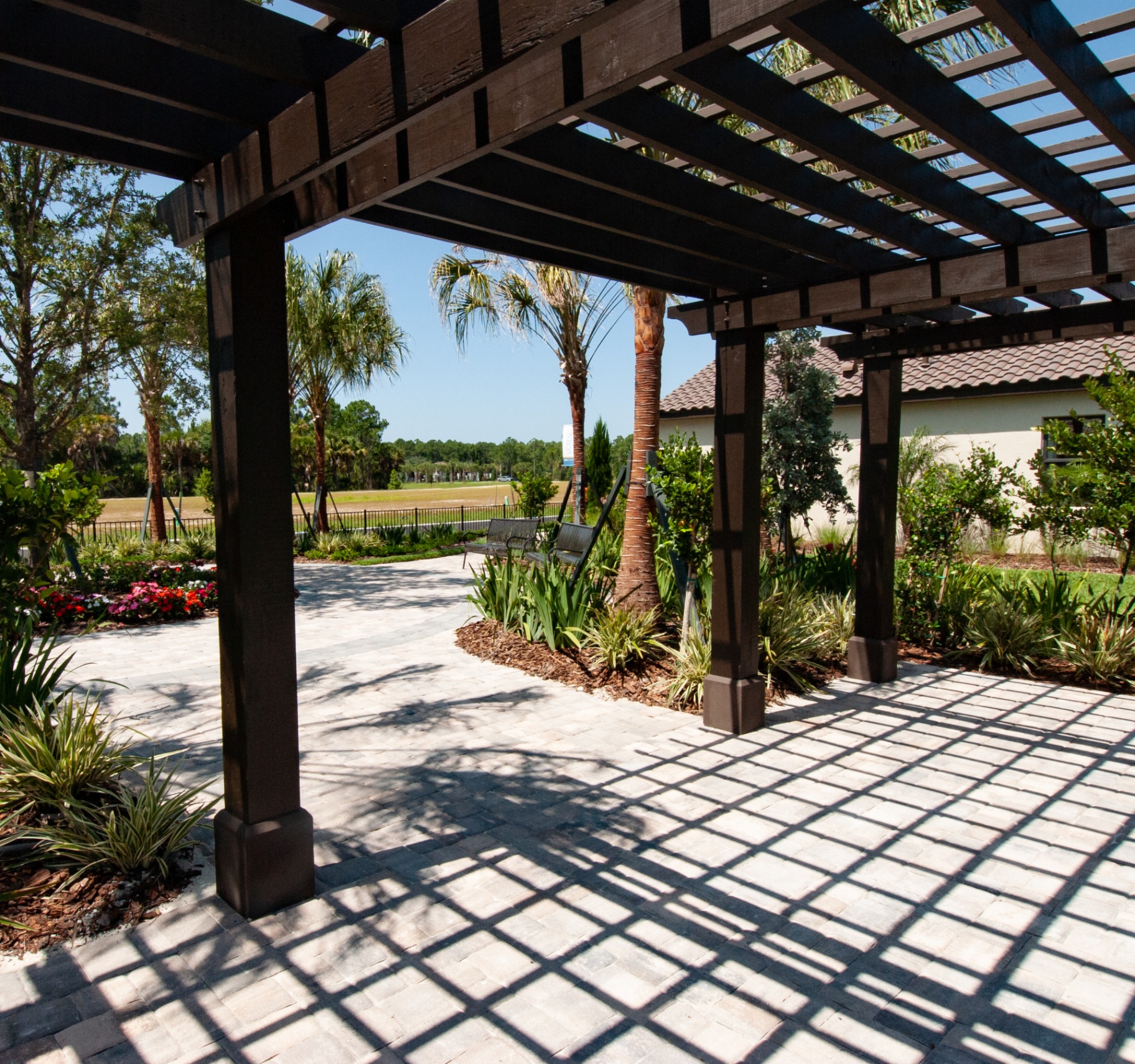 Shaded pergola and paver patio with flowering beds at Vicenza amenity center