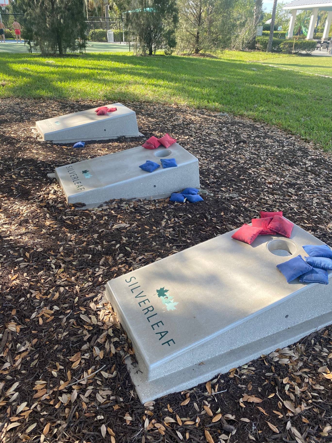 Branded concrete cornhole boards set in mulch beside the community amenity area