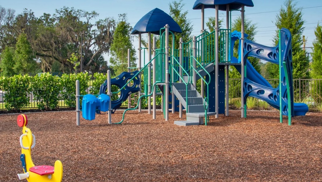 Shaded community playground with slides and climbing structures at Windward Lakewood Ranch