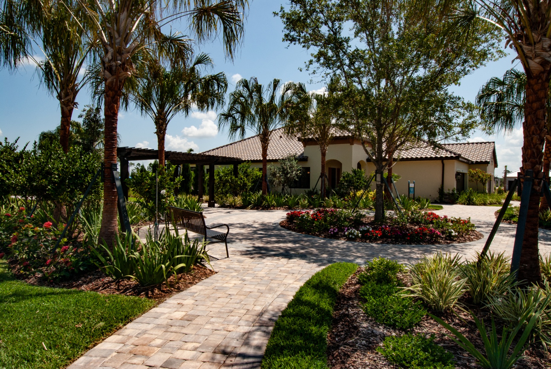 Multi-family courtyard with shaded pergola, paver paths, and blooming garden beds