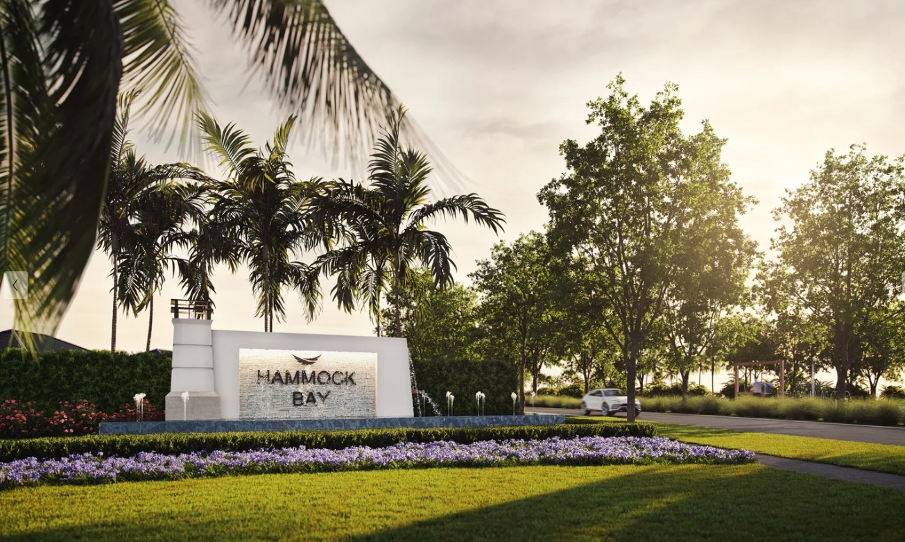 Hammock Bay monument sign framed by palms and flowering beds at golden hour