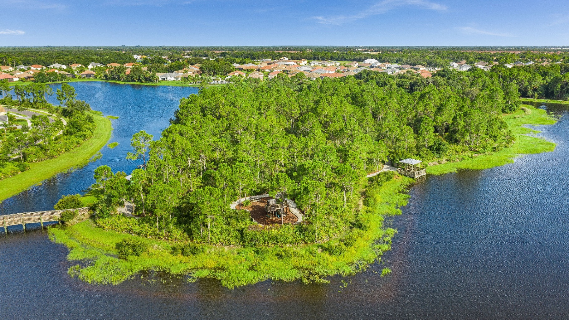 Aerial view of a lush green island park surrounded by water — community recreation and open space