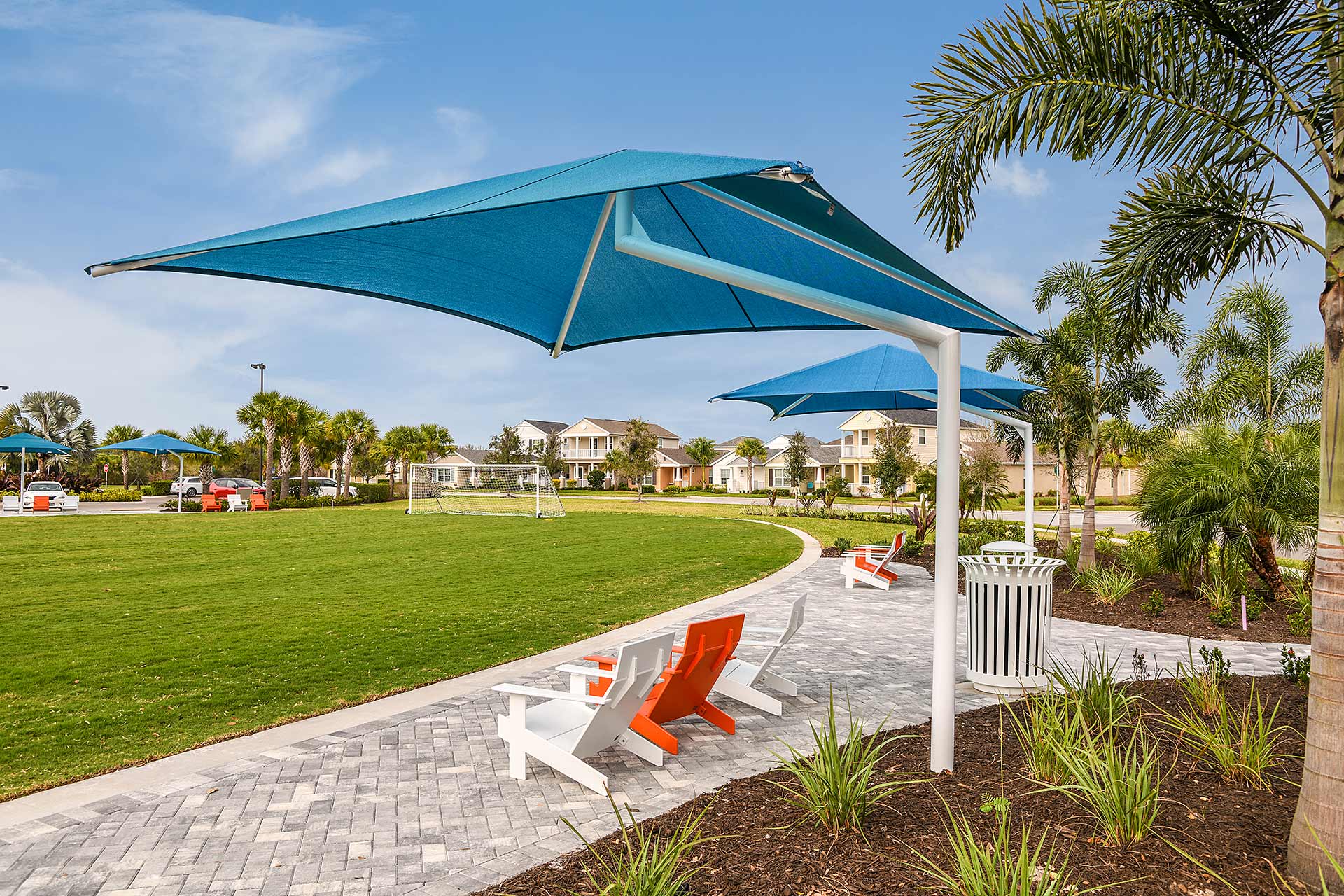 Shade sails over paver patio with Adirondack chairs at Silverleaf Symphony Park