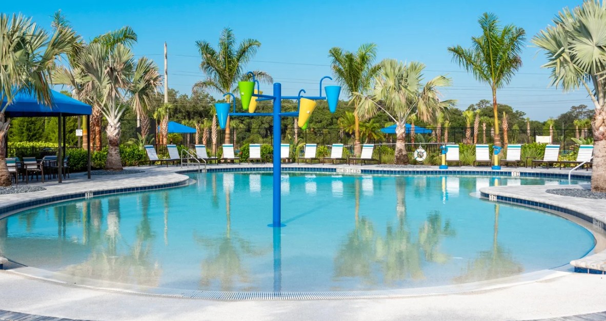 Zero-entry resort pool with splash features and palm-shaded lounge deck at Windward Lakewood Ranch