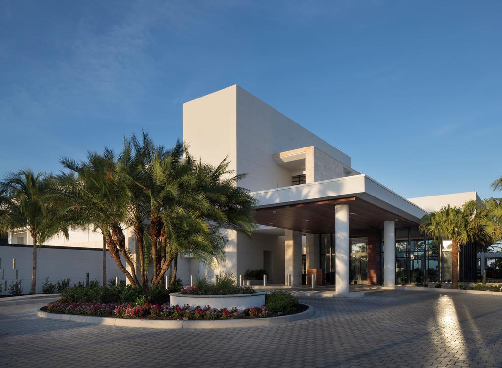 Zota Beach Resort porte-cochère with date palms, flowering roundabout planting, and paver drive