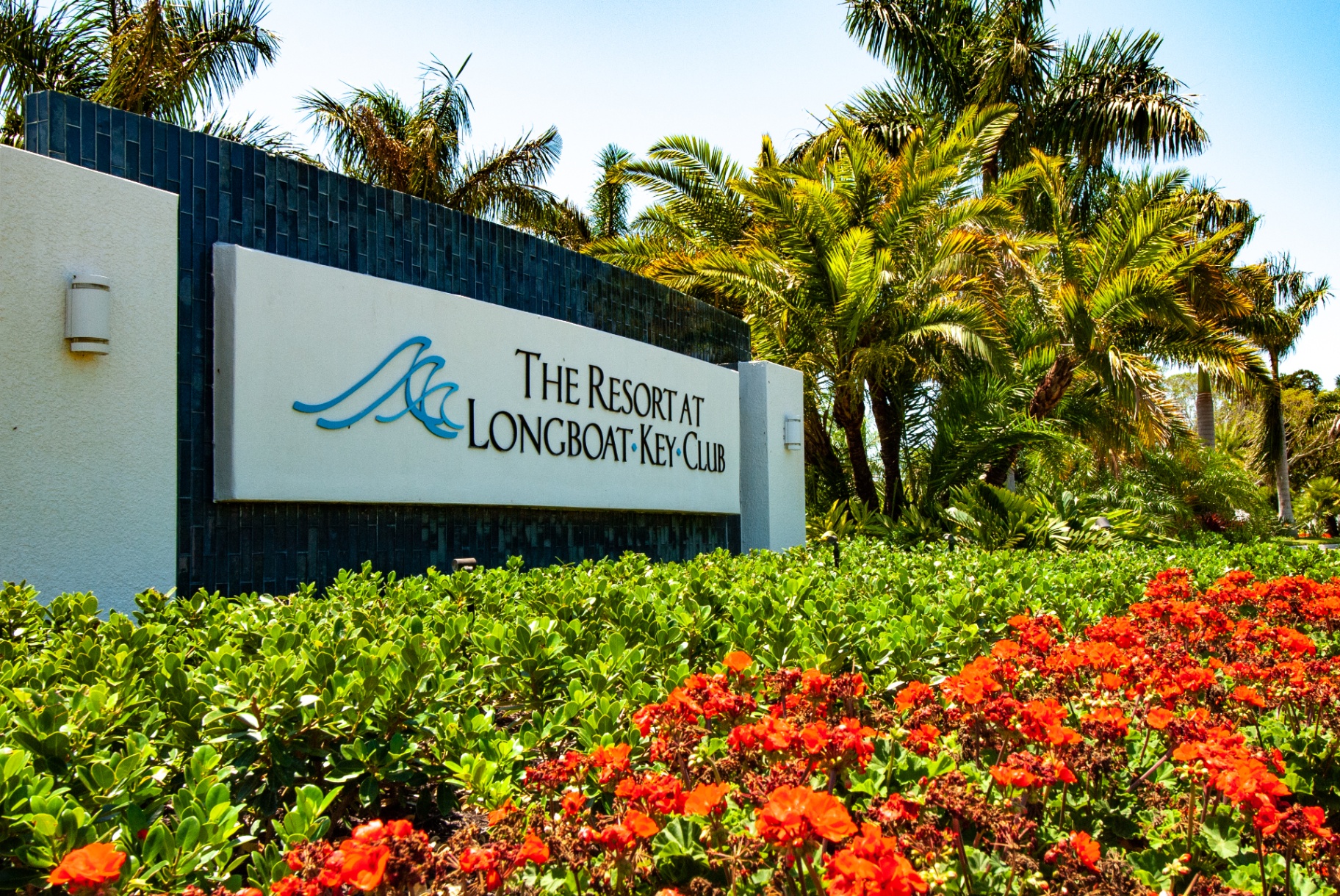 Entry monument sign at The Resort at Longboat Key Club framed by royal palms and tropical plantings